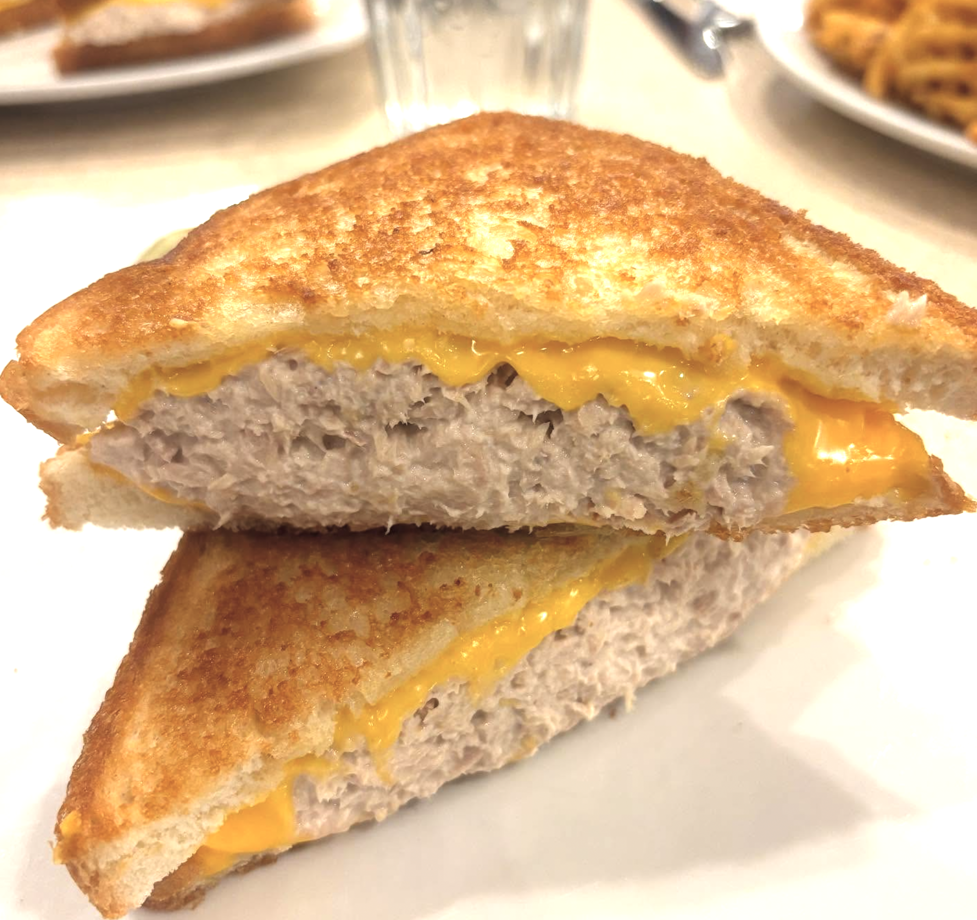 Close-up of a toasted tuna melt with melted cheddar.