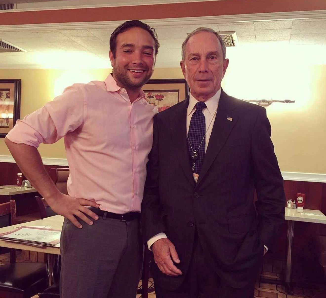 Former Mayor Michael Bloomberg standing inside Three Guys with a staff member.